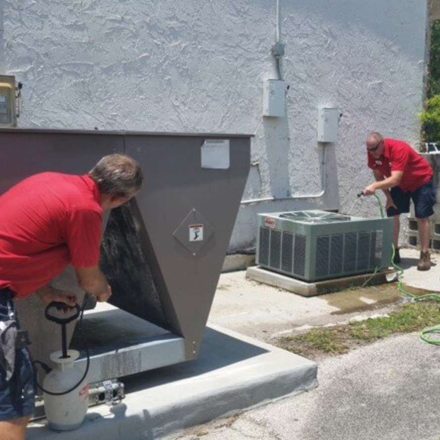 Atec Air & Heating technicians in branded uniforms servicing a commercial condenser unit